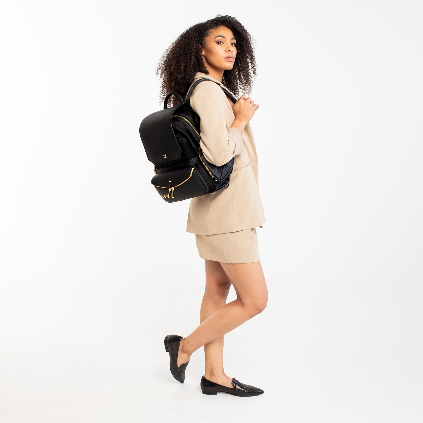 Woman wearing a Black-with-Gold-Hardware backpack.