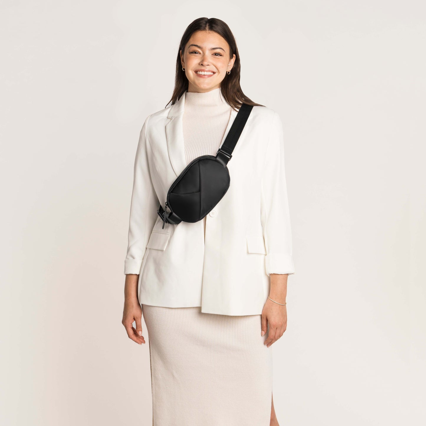 Woman wearing a white blazer and skirt with a black crossbody bag
