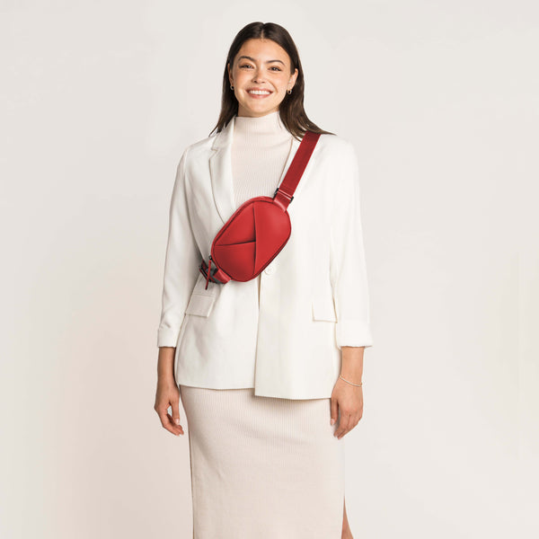 Woman wearing a white blazer and beige skirt with a Cardinal Red crossbody bag.