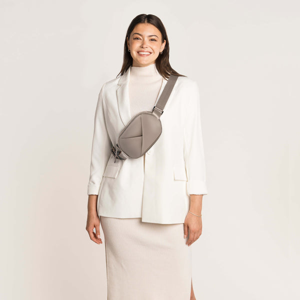 Woman wearing a white blazer and skirt with a Champagne Taupe crossbody bag.