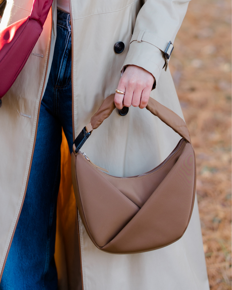 Person holding a brown leather handbag with a blurred background
