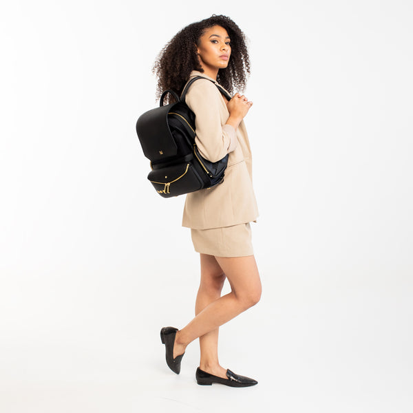 Woman wearing a Black-with-Gold-Hardware backpack.