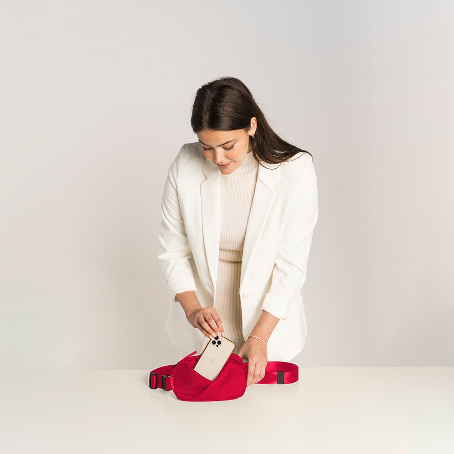 Woman holding a phone in a Cardinal Red waist bag.