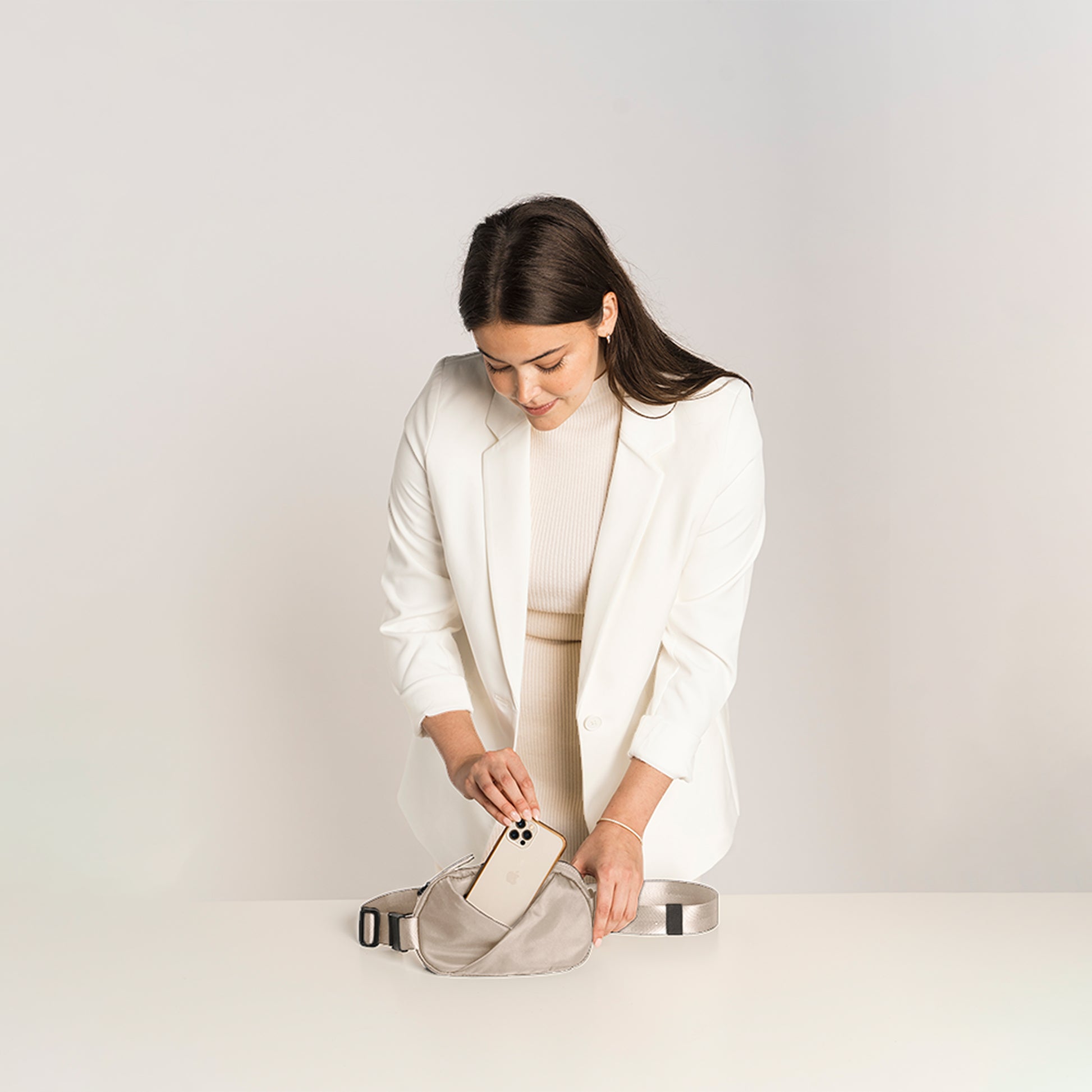 Woman in a white outfit with a Champagne Taupe fanny pack.