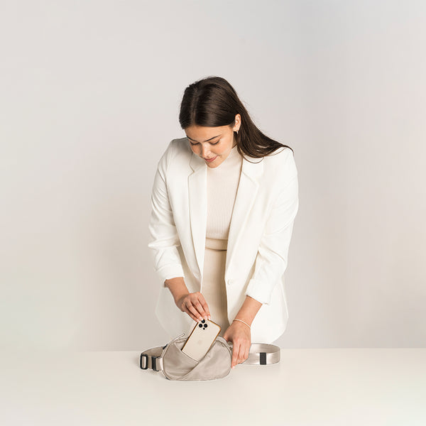 Woman in a white outfit with a Champagne Taupe fanny pack.