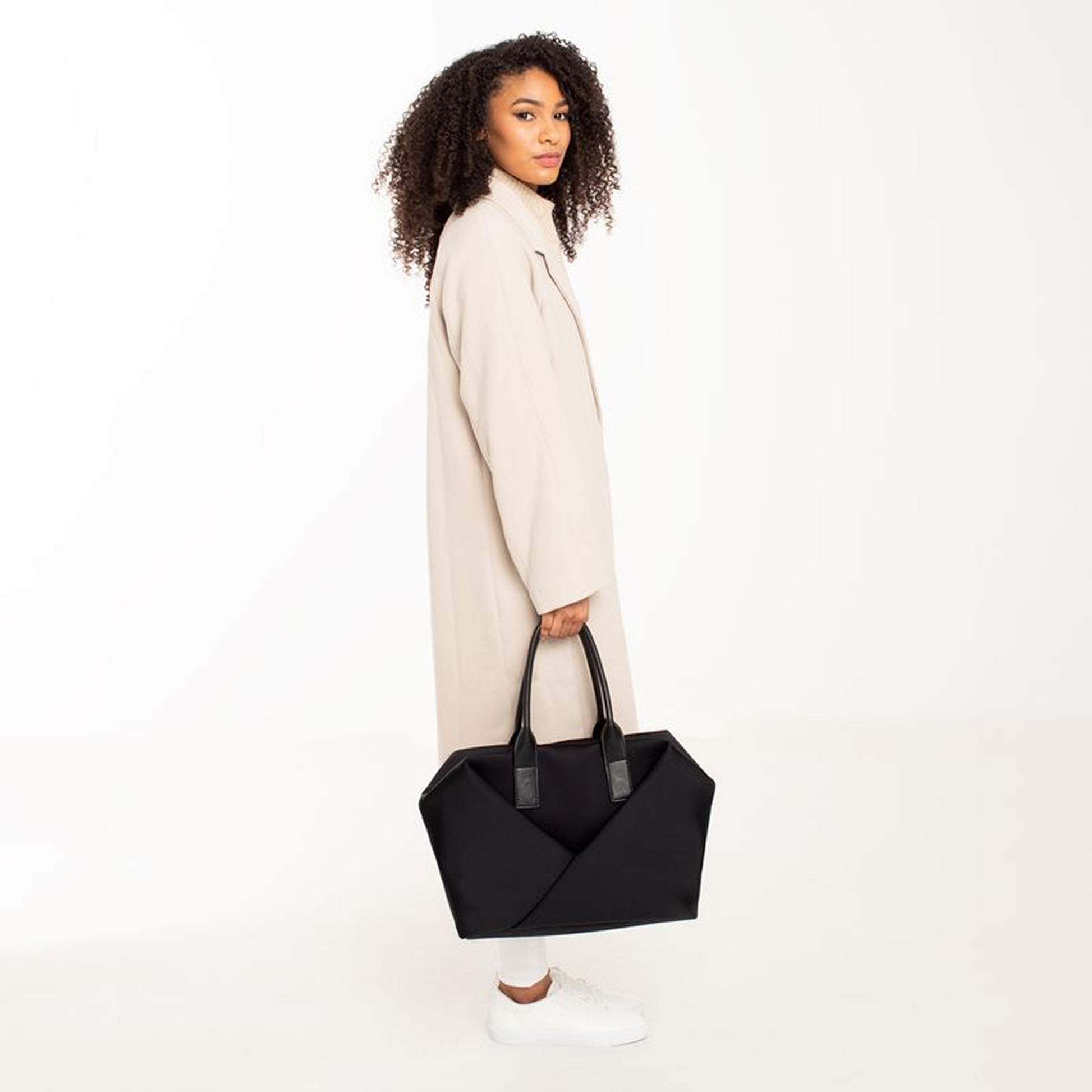 Woman holding a Lux & Nyx Large Origami Tote Ultra Matte - 15" Laptop Tote With Luggage Sleeve - Black + Gold Hardware 