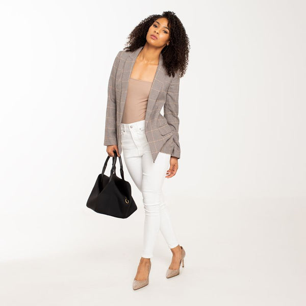 A lady stand with Black + Gold Hardware handbag.