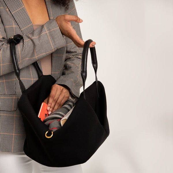 Person holding a Black + Gold Hardware handbag