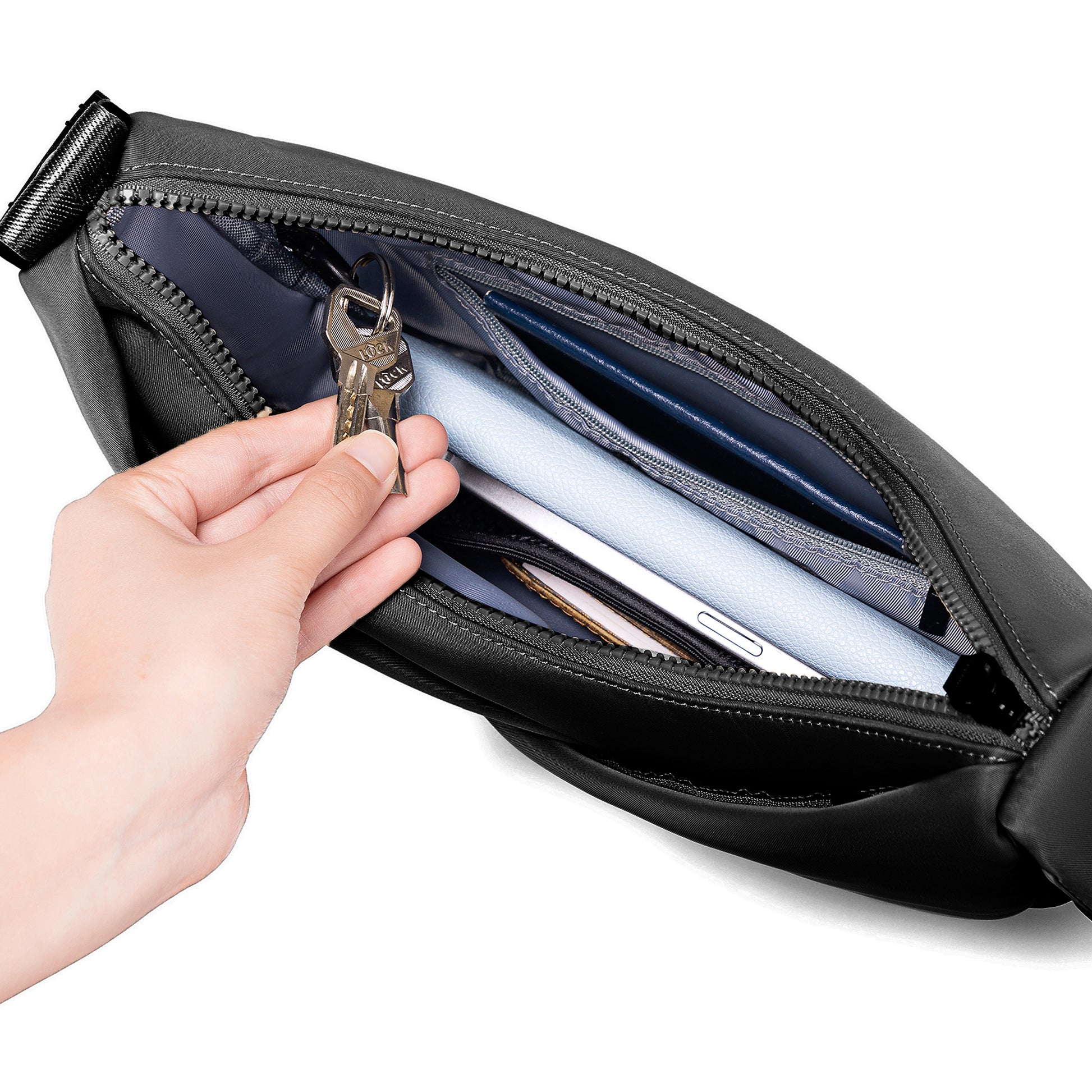 Hand opening a black waist bag to reveal its contents on a white background
