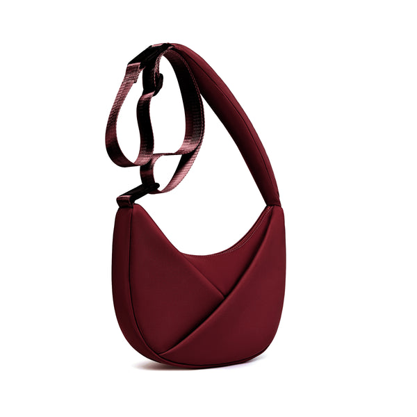 Burgundy handbag with a strap on a white background