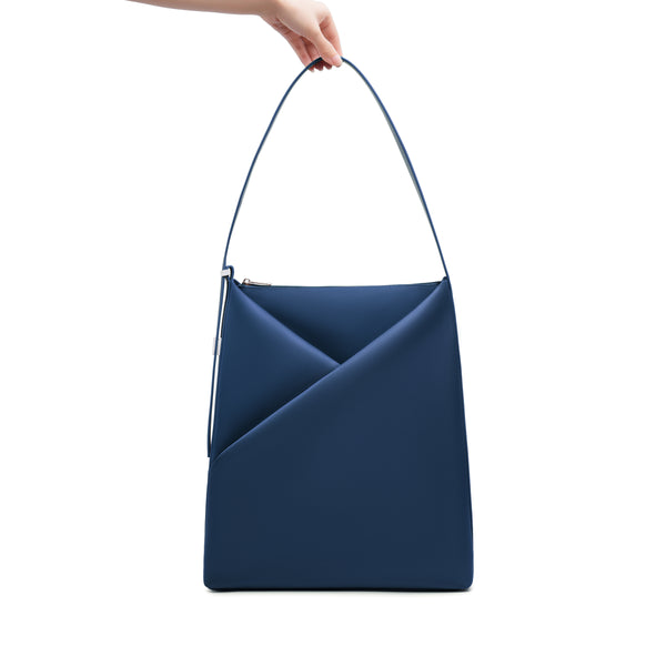 Navy Blue Origami Hobo Bag held by its handle, emphasizing the structured origami silhouette.
