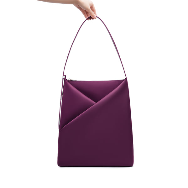 Wine Origami Hobo Bag held by its handle, emphasizing the structured origami silhouette.
