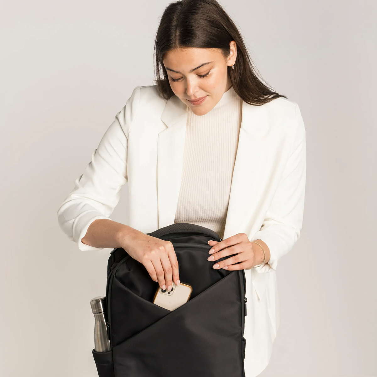 Lux & Nyx Origami Backpack - 16" Laptop Backpack With Trolley Strap - Black - Professional Woman Putting A 16” Laptop Backpack in The 16” Padded Laptop Compartment