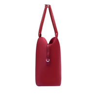 Side profile of a crimson red origami handbag highlighting its slim depth, arched top handles, and clasp closure.
