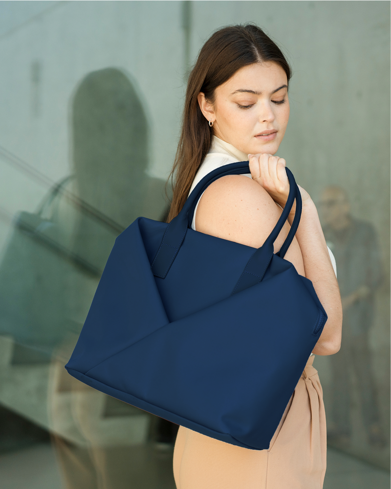 Woman carrying a navy blue tote bag in an urban setting