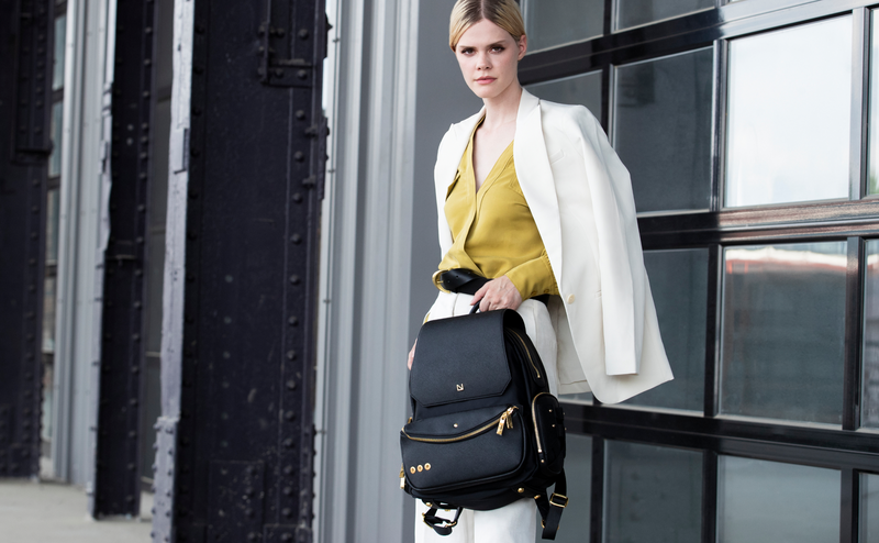 Woman holding a black handbag against a modern building background