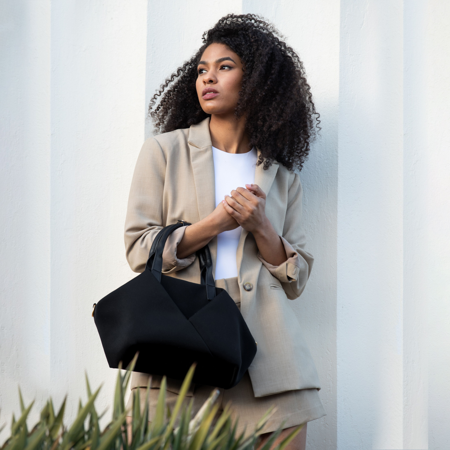 A lady carry Mid Origami handbag in her hands. Available in black with gold hardware
