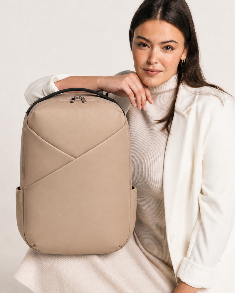 Woman holding a beige backpack against a white background