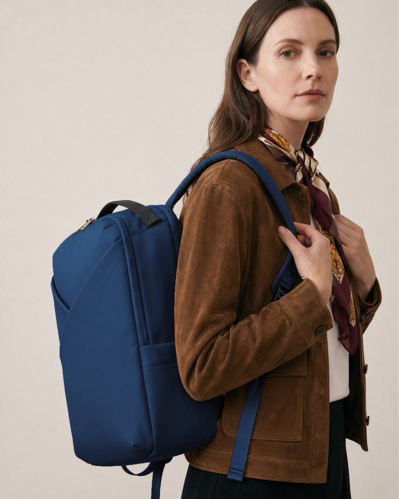 Woman wearing a blue backpack against a plain background