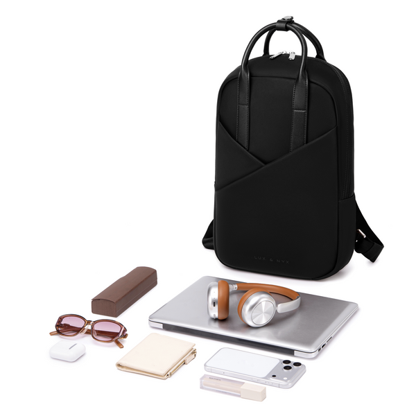 Origami Slim Black Backpack with contents laid out — laptop, sunglasses, cosmetics, earbuds, pen — showing total capacity