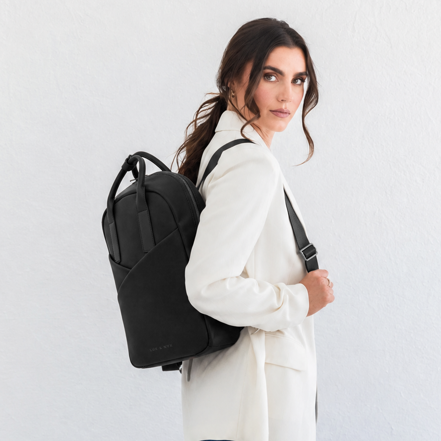 Woman wearing black Origami Slim Black Backpack over one shoulder