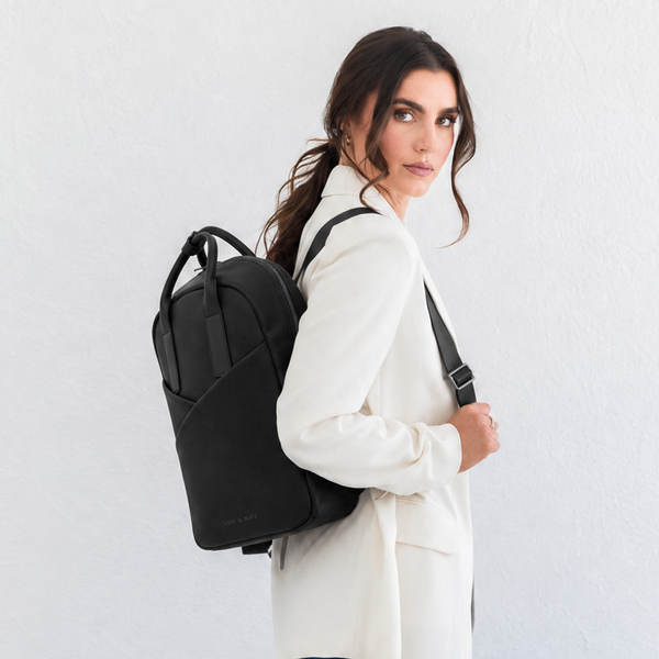 Woman wearing black Origami Slim Black Backpack over one shoulder