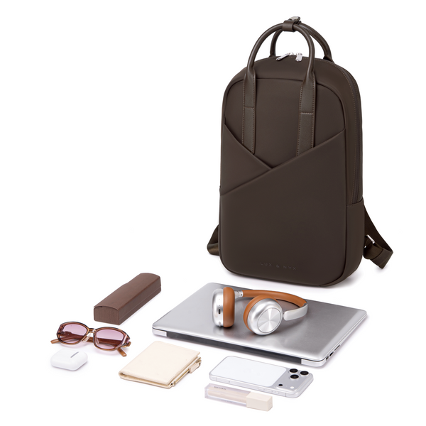 Origami Slim Espresso Backpack with contents laid out — laptop, sunglasses, cosmetics, earbuds, pen — showing total capacity