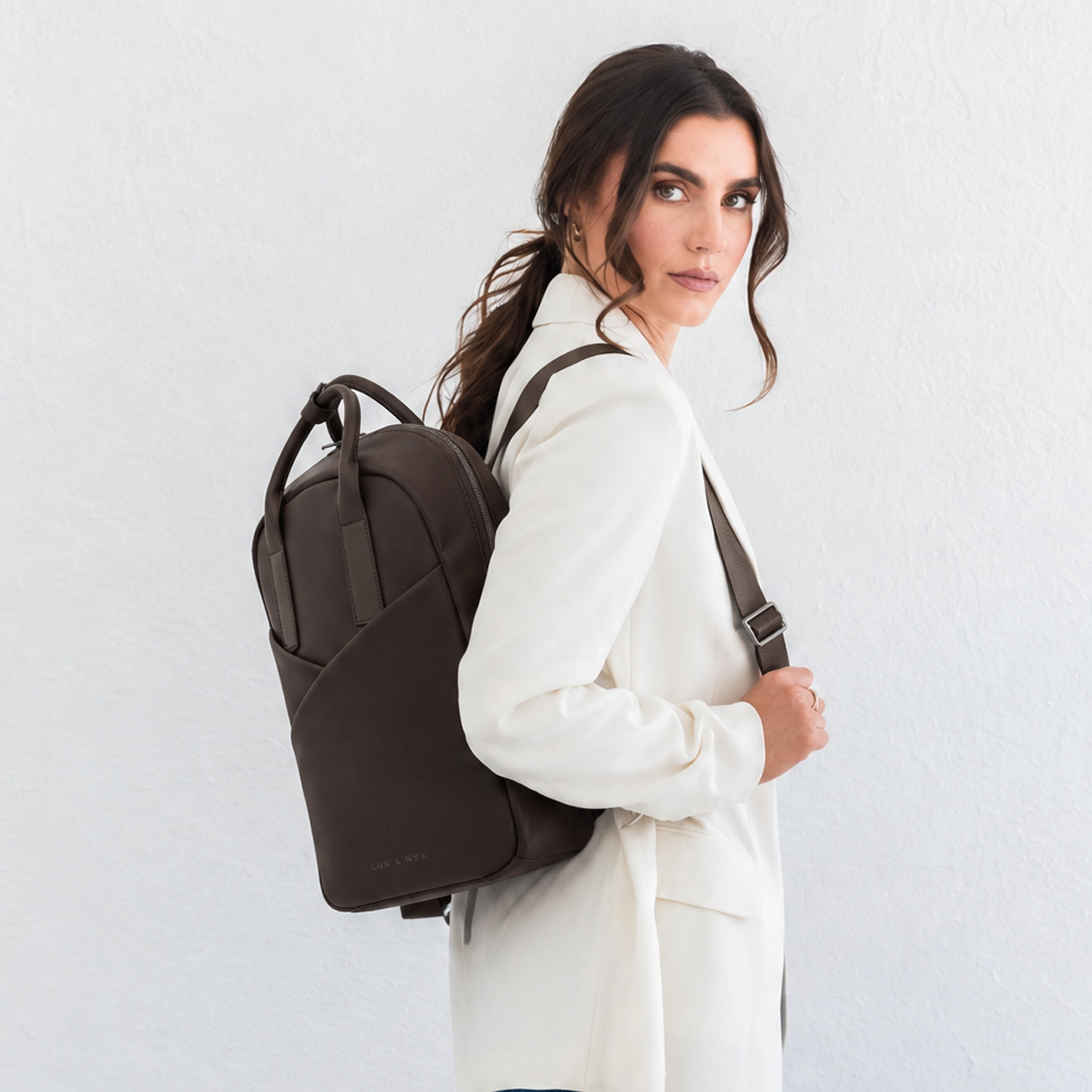 Woman wearing espresso Origami Slim Backpack over one shoulder