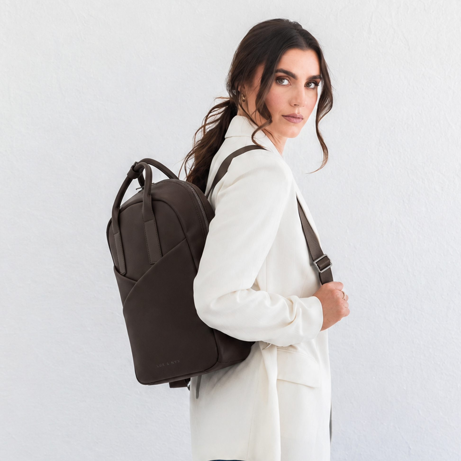 Woman wearing espresso Origami Slim Backpack over one shoulder