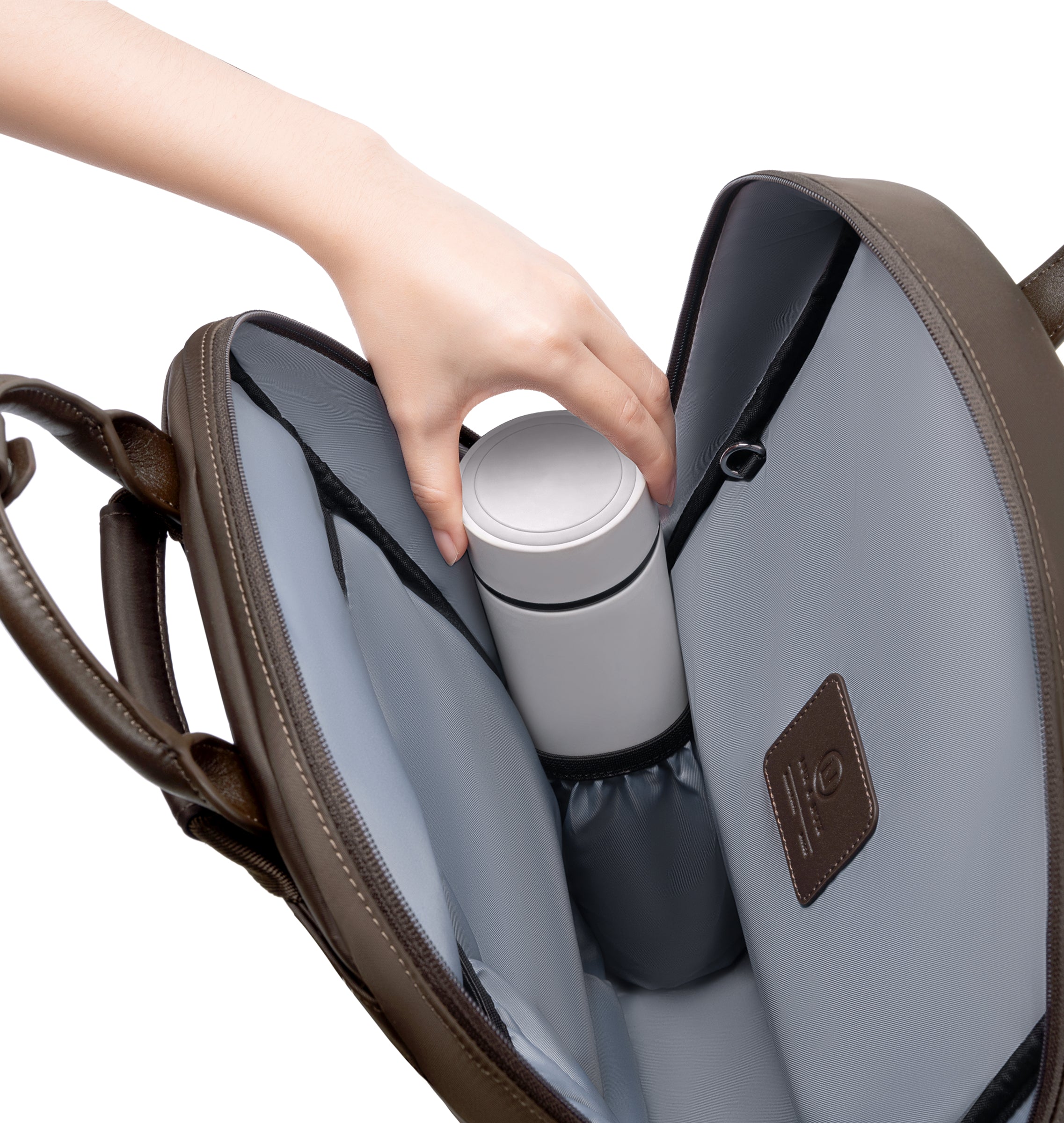 Hand placing a reusable water bottle into the dedicated interior bottle pocket of an espresso backpack, showcasing organized storage and easy access inside the spacious main compartment.