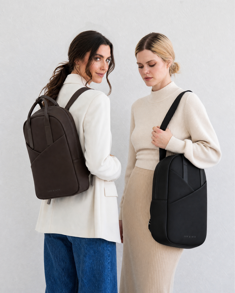 Two women wearing different types of bags against a plain background