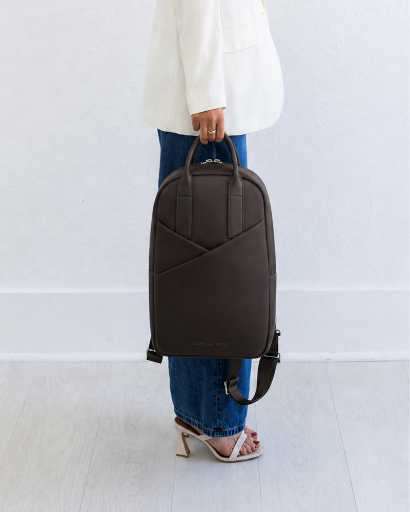 Person holding a black backpack against a white background