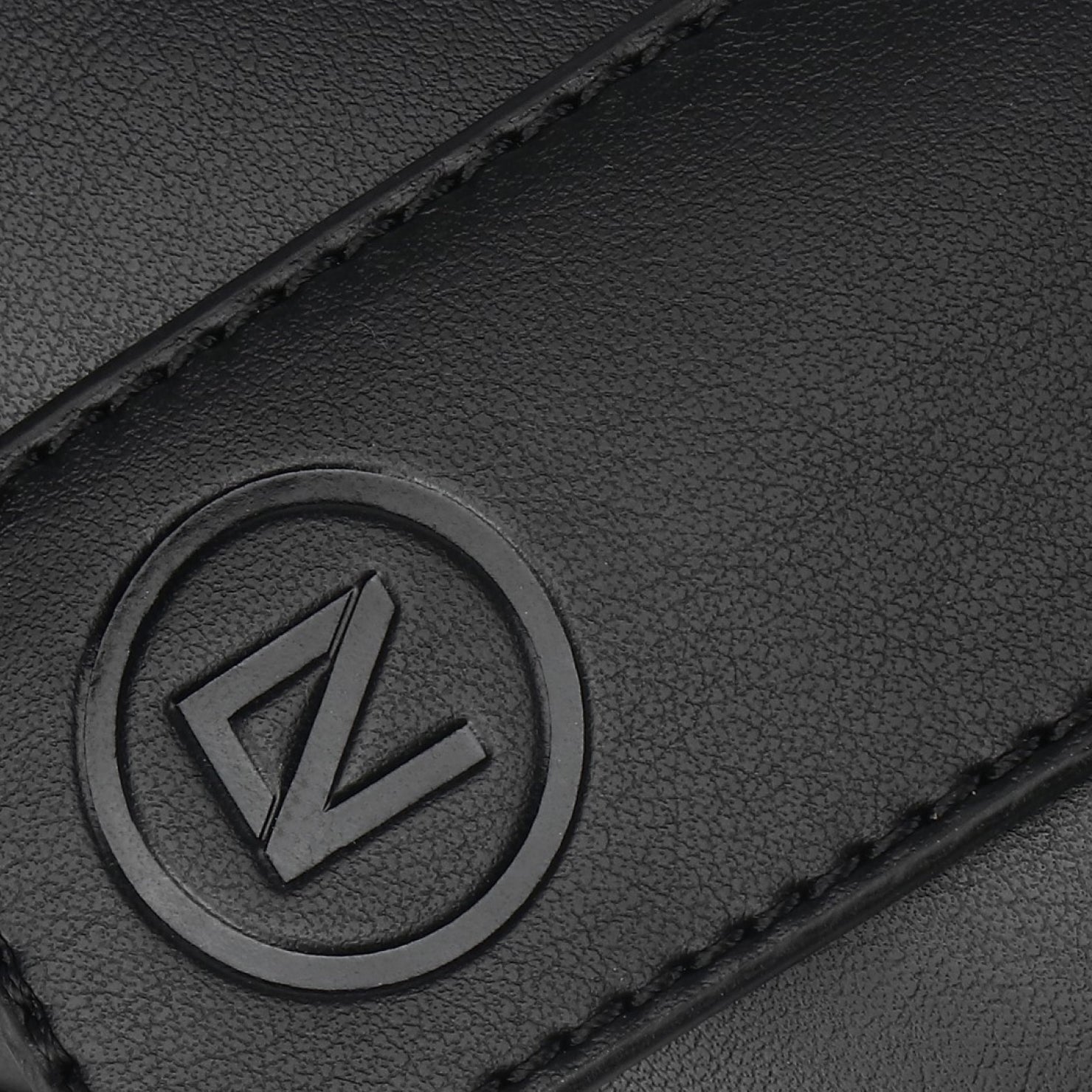 Close-up of a black leather product with a logo on a dark background