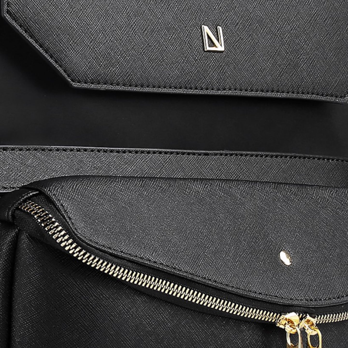 Close-up of a black bag with a gold zipper and brand logo on a dark background