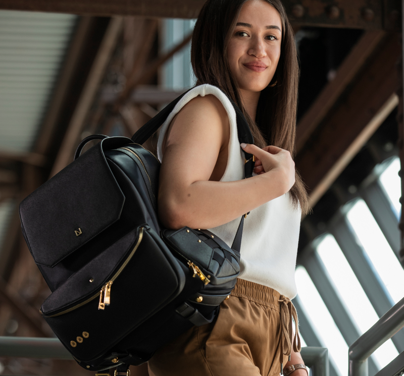 Woman carrying a black backpack in an indoor setting with wooden beams.