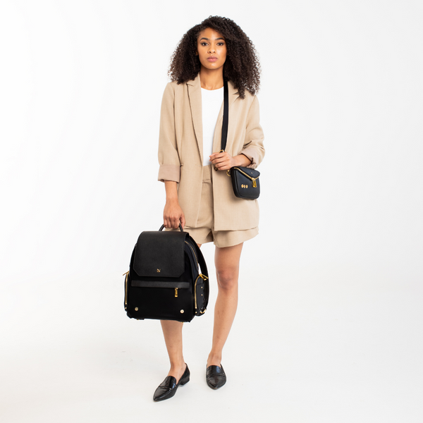 Lux & Nyx Zoe Backpack - 15" Laptop Backpack With Detachable 5-Way Wear Crossbody Clutch - Black-with-Gold-Hardware - A Professional Woman Holding The Backpack And Wearing The Detachable 5-Way Wear Crossbody Clutch in Crossbody Mode On Her Shoulder